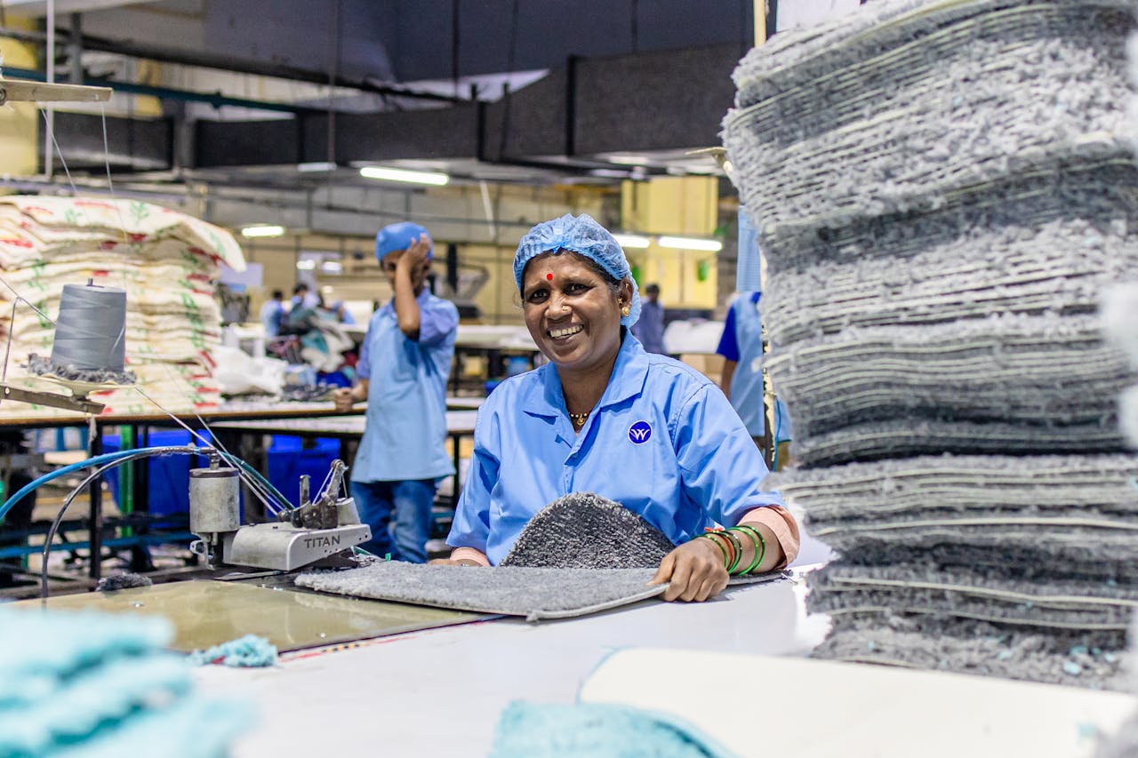 our-story Joyful textile worker in a bustling factory, showcasing the vibrant workplace environment.