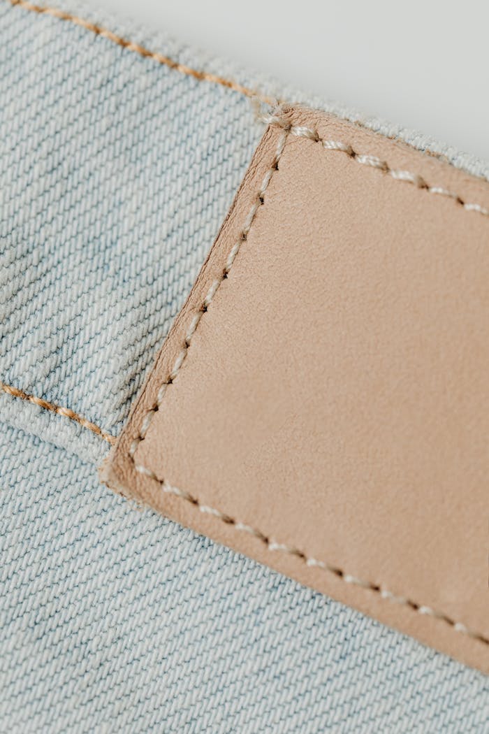 services-01 Detailed shot of a denim fabric showing a jacron leather patch with stitches, ideal for fashion concepts.